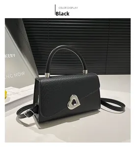 Dettaglio borsa in pelle nera con chiusura a girello in metallo argentato a forma di cuore