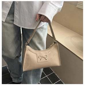 Dettaglio borsa a spalla in pelle verniciata beige con fiocco in metallo dorato
