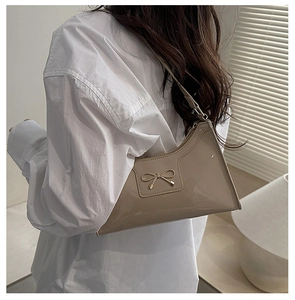 Dettaglio della borsa a spalla in pelle verniciata color albicocca con fiocco in metallo