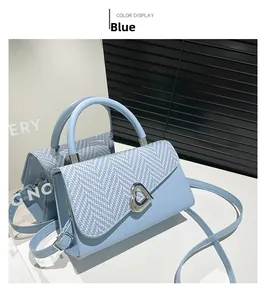Dettaglio borsa azzurra con patta intrecciata, chiusura a cuore in metallo e tracolla