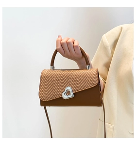 Dettaglio di una borsa patchwork marrone con patta intrecciata e lucchetto a cuore argento