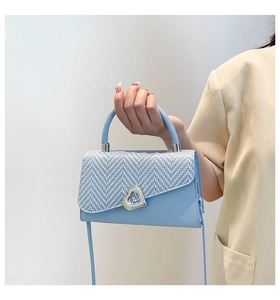 Dettaglio borsa a tracolla azzurra con patta in tweed e chiusura a cuore in metallo argento