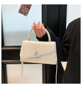 Dettaglio della borsa beige che mostra il patchwork e la chiusura a cuore in metallo
