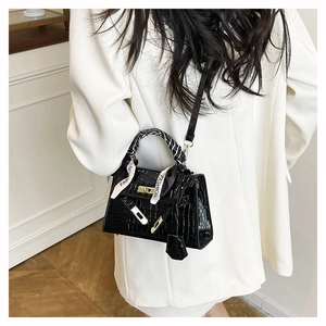 Detail of black crocodile texture handbag with gold lock and fashion printed silk scarf