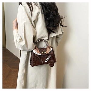 Detail of dark brown croc-pattern Kelly bag with gold lock and fashion silk scarf handle