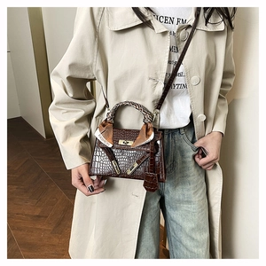 Détail du sac à main marron foncé texture crocodile avec foulard sur la poignée