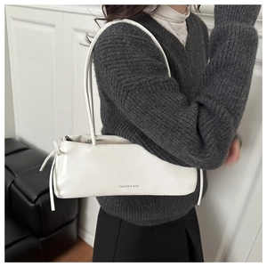 Dettaglio di una borsa sottobraccio in pelle bianca con lunghe frange e spalline sottili