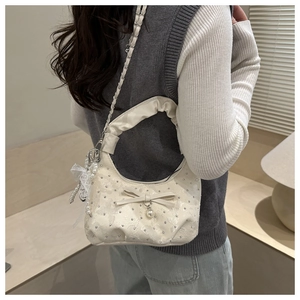 Dettaglio di una borsa arricciata con fiocco, perla e catena d'argento sul modello