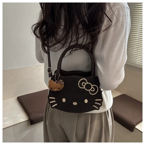 Detailed view of black leather handbag with embroidered cat face and plush leopard charm