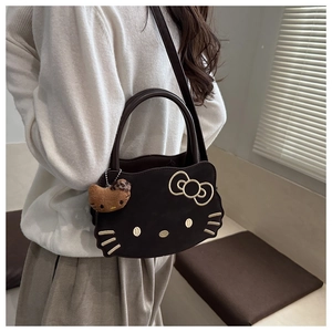 Detail of dark brown Hello Kitty embroidery shoulder bag with plush charm on a model