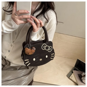 Close-up of a brown cat-shaped handbag with gold embroidery and a plush charm