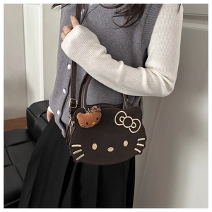 Detail of a brown cat-shaped handbag featuring a cute leopard print charm and a top handle