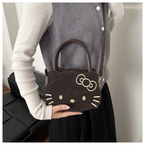 Detailed close-up of dark brown Hello Kitty shaped handbag with adjustable shoulder strap