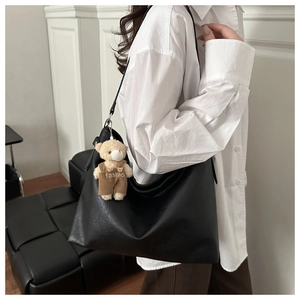 Detail of a large black Hobo bag with a textured finish and cute bear plush charm