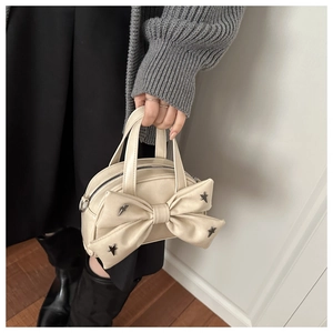 Dettaglio della borsa in similpelle crema con grande fiocco e borchie a stella