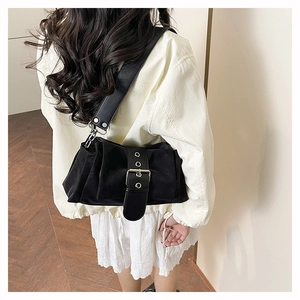 Detail view of black pleated baguette bag with large silver buckle and wide strap