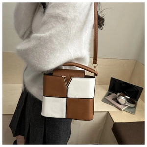 Detail view of contrast color bucket bag with gold V-hardware and lychee leather texture