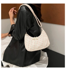 Dettaglio di una borsa a spalla in velluto a coste crema con motivo a fiocchi rosa