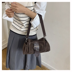 Détail du sac sous le bras en daim marron foncé avec large bandoulière et boucle