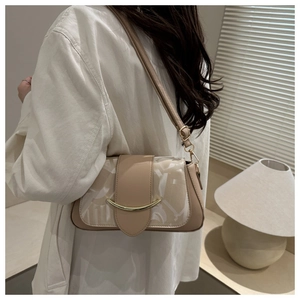 Detail der beige Schultertasche mit Goldschmuck und Logomuster am Modell