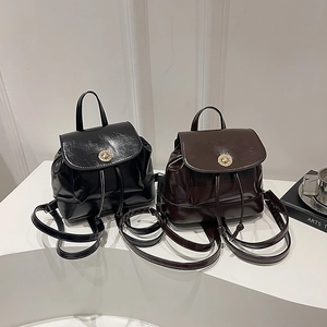 Mini PU leather backpacks in black and dark brown with golden ring buckles on a white pedestal