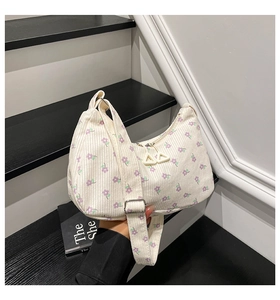 Dettaglio della borsa a mezzaluna in velluto a coste bianco con fiori viola