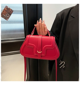Dettaglio della borsa a sella in pelle rossa martellata con patta a onde e fibbia dorata