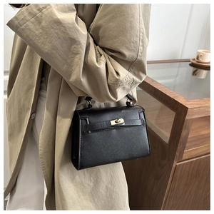 Detail of a chic black textured leather handbag styled with a khaki trench coat