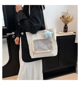 Detalle del bolso tote blanco con bolsillo de malla y colgante de estrella decorativo