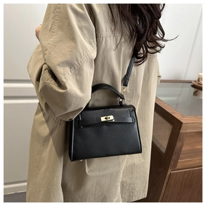 Classic black leather handbag with gold twist lock and crossbody strap on a model