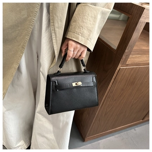 Detailed view of the black lychee pattern leather handbag with gold rotating clasp