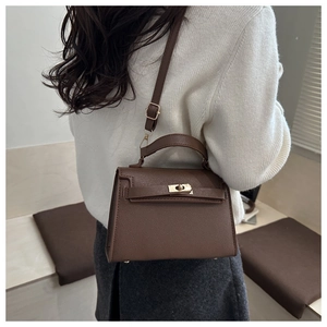 Detail of vintage textured dark brown crossbody bag with metal twist lock and top handle