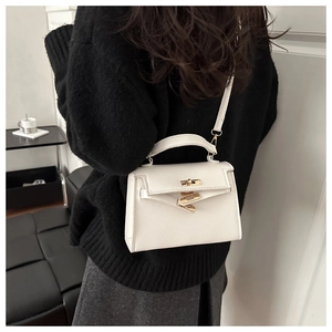 White lychee leather trapezoid handbag with gold hardware worn by model on shoulder