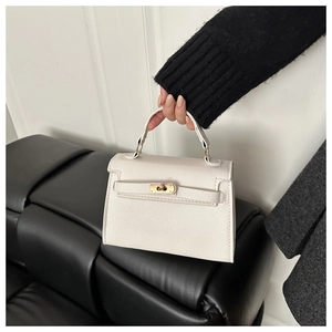 Detail of white leather mini bag with golden buckle and handle held by model