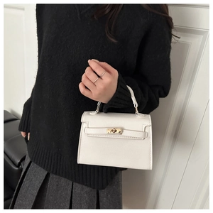 Detailed shot of a white leather crossbody bag with a gold metal twist lock buckle