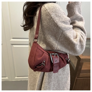 Close-up of retro burgundy shoulder bag with metallic buckle and soft suede texture
