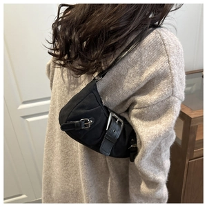 Dettaglio della borsa a spalla plissettata nero opaco con fibbie metalliche e stile punk