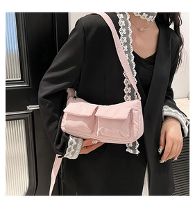 Borsa a tracolla rosa in nylon con due tasche a patta indossata su un completo nero