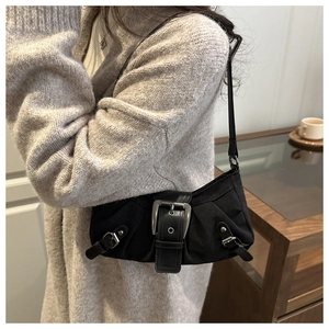 Detail of black retro shoulder bag with large silver buckle on a stylish model