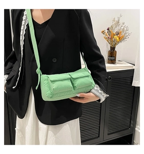 Dettaglio borsa a tracolla in nylon verde chiaro con doppie tasche utility su blazer nero
