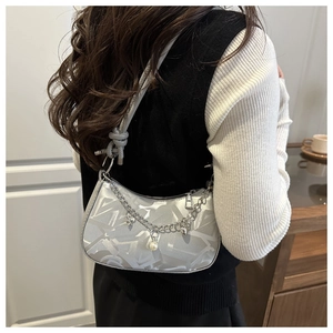 Detail of silver underarm bag with metallic star charms and pearl chain strap
