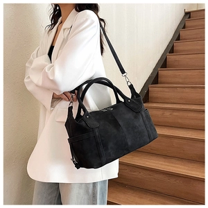 Dettaglio di una borsa Boston in pelle opaca nera con manici robusti e tracolla sottile