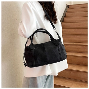 Modello che indossa una grande borsa tote nera con tracolla regolabile su scale di legno