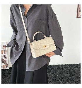 Dettaglio di borsa beige intrecciata con chiusura dorata e tracolla regolabile fine