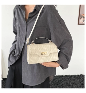 Detail of off-white woven crossbody bag showing metal clasp and adjustable strap