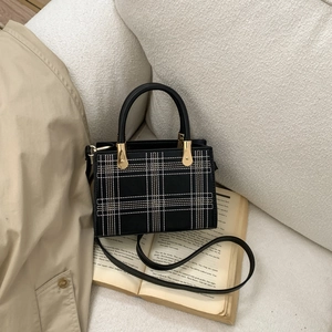 Borsa a tracolla vintage nera con ricamo a quadri e dettagli dorati su un libro