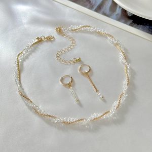 Dettaglio di un set collana cuore dorata con cristalli su tessuto di seta bianca