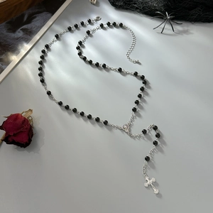 Gothic rosary necklace with black beads and silver cross pendant on Halloween theme background