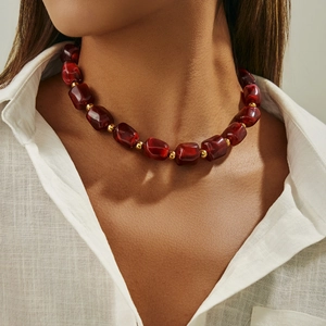 Dettaglio di perle in resina rossa traslucida con accenti dorati sul collo del modello
