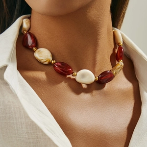 Dettaglio collana con grandi perle di resina rossa e marmorizzata e sfere dorate
